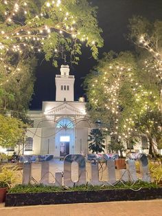 a large building with lights on the front and trees around it that are decorated in letters