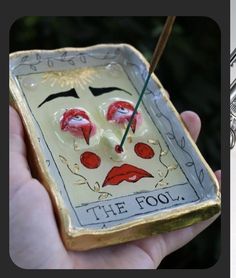 a hand holding a small ceramic box with some paint on it and the words, the fool