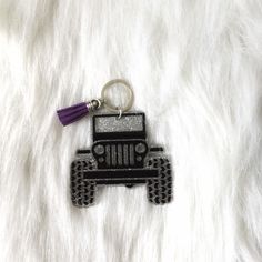 a black jeep keychain with a purple tassel hanging from it's side