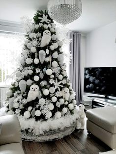 a white christmas tree in a living room decorated with snowflakes and owl ornaments