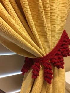 a curtain with red crochet trim hanging from it's side in front of a window