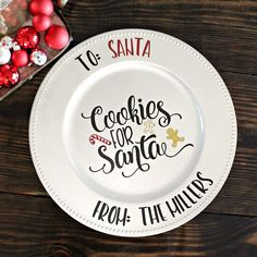 a white plate with the words cookies for santa on it next to some christmas ornaments