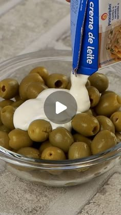 a bowl filled with green olives next to a carton of mayonnaise