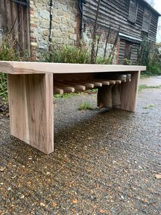 a wooden bench sitting on top of a gravel road next to a building and trees