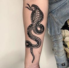 a black and white snake tattoo on the left arm, next to a man's leg