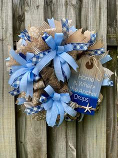 a blue and tan wreath with a tag hanging on the side of a wooden fence