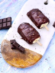 three chocolate covered popsicles sitting on top of a cutting board