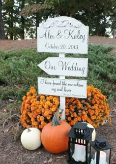 a sign that is sitting in the grass with pumpkins and flowers behind it,