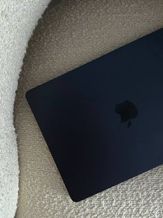 an apple laptop computer sitting on top of a white carpet