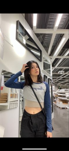 a woman standing in front of a white wall wearing a gray and blue crop top