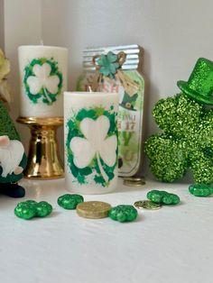 green shamrocks and candles are sitting on a table next to other decorations, including a st patrick's day candle