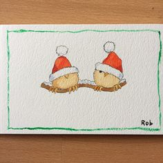 a drawing of two birds wearing santa hats on top of a piece of white paper