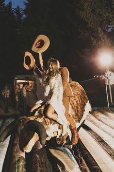 a man and woman riding on the back of a cow