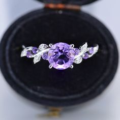 an amethorate ring in a black velvet box with silver leaves on it