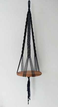 a wooden shelf with black rope hanging from it's sides on a white wall