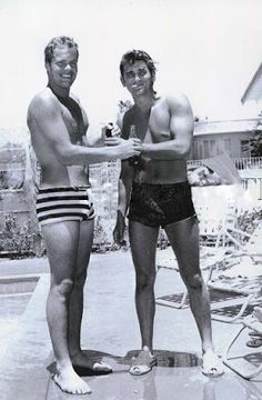 two men standing next to each other near a pool