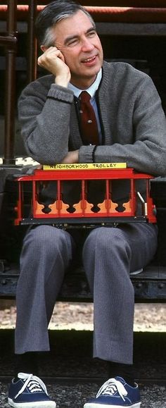 a man sitting on top of a train with his hands in his ears while talking on the phone