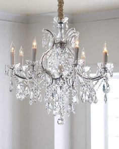 a chandelier hanging from the ceiling in a room with white walls and windows