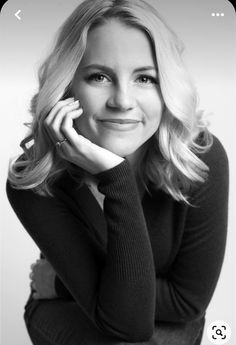 a black and white photo of a woman with her hand on her chin looking at the camera