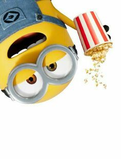 a minion eating popcorn from a red and white striped bag with his eyes wide open