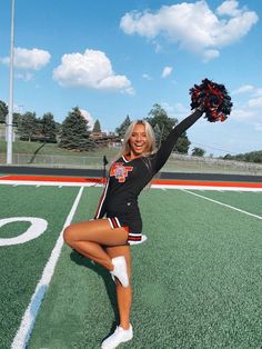 the cheerleader is posing on the field with her pom - poms in hand