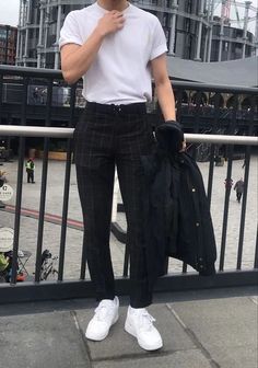 The image features a man wearing a crisp white t-shirt paired with stylish black checkered trousers. He completes the look with white sneakers and holds a black jacket in his hand. The outfit strikes a perfect balance between casual and trendy, suitable for an urban setting. The background, featuring modern architecture, enhances the contemporary feel of the ensemble.  #MensFashion #UrbanStyle #MonochromeLook #CasualChic #StreetStyle #OOTD #FashionInspiration #BlackAndWhite #CheckeredPants #ModernFashion Mens Trendy Outfits, Elegante Casual, Mens Fashion Streetwear, Ideas Photography, Mens Fashion Casual Outfits, Adidas Outfit, Men Fashion Casual Outfits, Streetwear Men Outfits