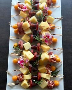 appetizers are arranged on skewers with meat and cheese, garnished with fresh herbs