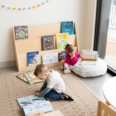 two children sitting on the floor reading books