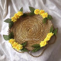 a basket with yellow flowers on it sitting on a white cloth covered tablecloth next to a gold chain