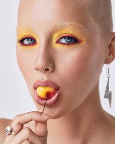 a woman with yellow makeup and piercings on her nose