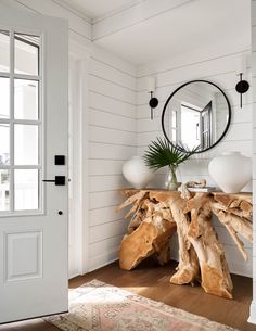 a wooden table topped with a mirror next to a white door in a living room