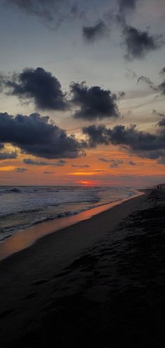 the sun is setting over the ocean with clouds in the sky