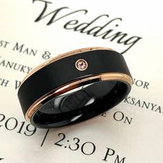 a black and gold wedding band with a diamond in the center on top of a newspaper