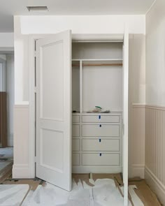 an empty closet with white doors and drawers on the floor in front of it is being remodeled