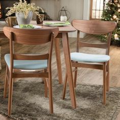 two wooden chairs sitting at a table in front of a christmas tree