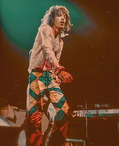 a man with long hair standing on top of a stage