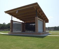 a covered pavilion in the middle of a grassy field