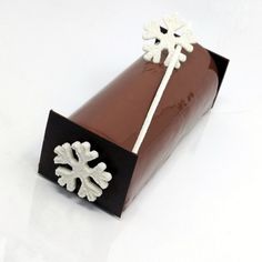 a chocolate box with white snowflakes on it's wrapper and ribbon