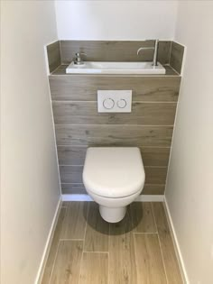 a white toilet sitting in a bathroom next to a sink and wooden paneled walls