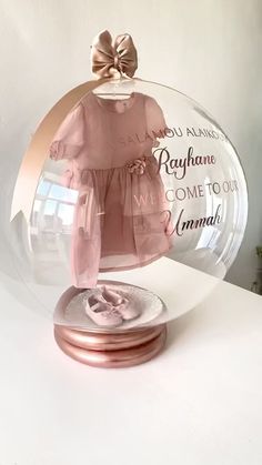 a glass dome with a baby's pink dress on it and the words, rayhane come to our mama