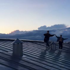 two people standing on top of a metal roof