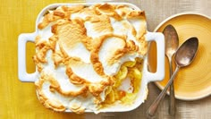 a casserole dish on a yellow table with spoons