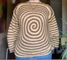 a woman standing in front of a mirror wearing a sweater with a spiral design on it