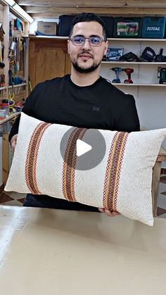 a man holding a pillow in his workshop