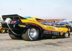 an orange and black race car sitting on top of a parking lot