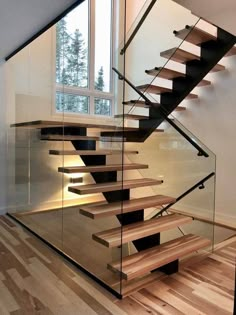 a glass stair case with wooden steps in front of a window and wood flooring