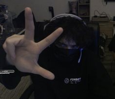 a person wearing a face mask and making the peace sign with their hands in front of them