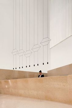 a man in a suit is sitting on a ledge and looking up at the ceiling