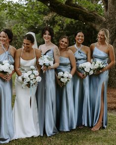 a group of women standing next to each other in front of a tree with white flowers