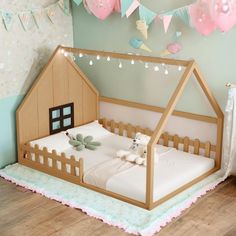 a wooden dollhouse bed with white sheets and pillows